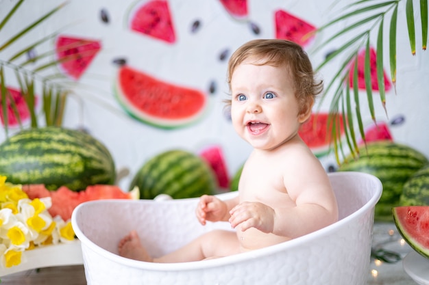 A baby a girl a closeup portrait against a background of watermelons laughing and rejoicing