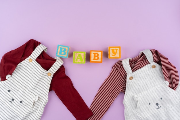 Baby girl clothes on lilac pastel background