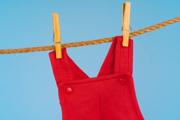 Baby girl clothes pinned on a clothesline against blue background