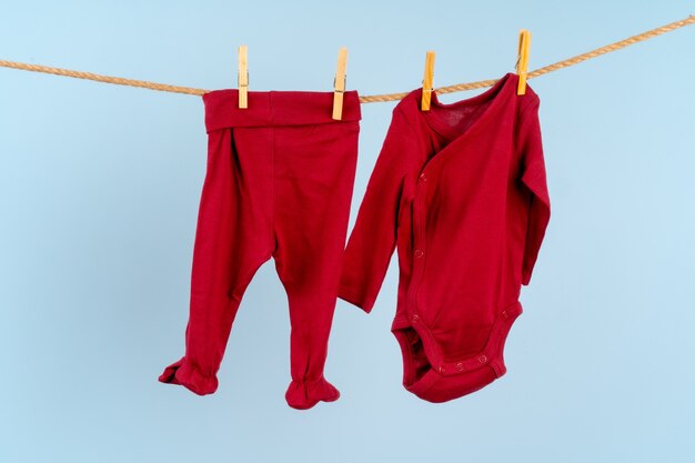 Baby girl clothes pinned on a clothesline against blue background