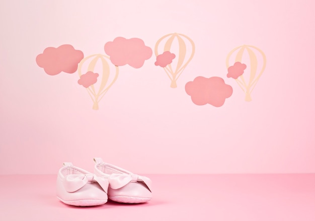 Photo baby girl cute pink shoes over the pink pastel background with clouds and ballons