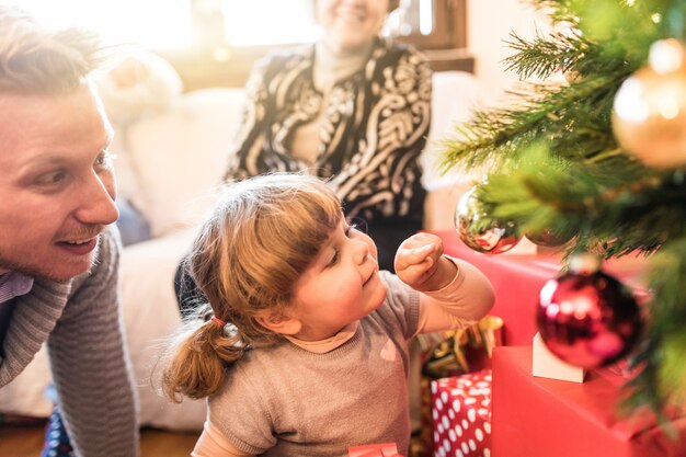女の赤ちゃんとクリスマスツリーの飾りで遊んでお父さん