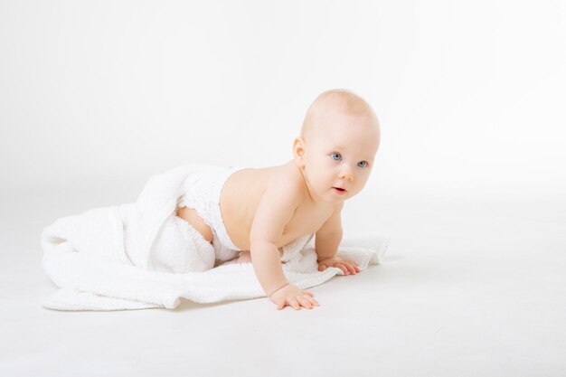 A baby girl in a diaper crawls isolated on a white background