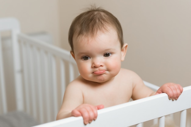 Baby girl in a diaper playing in the crib.