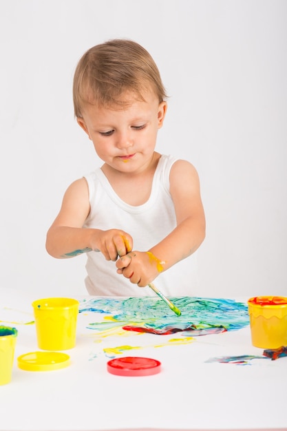 아기 소녀는 손가락 페인트를 그립니다.