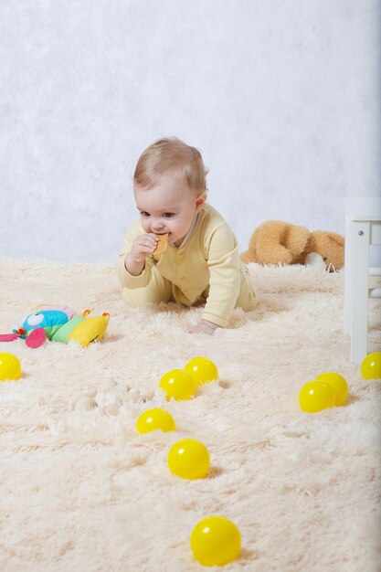 A baby girl of eight months dressed in a yellow pyjama plays in her room