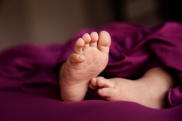 Baby girl feet on raspberry, closeup of barefeet