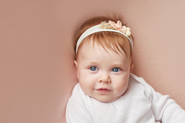 Baby girl of four months lies on a light pink wall