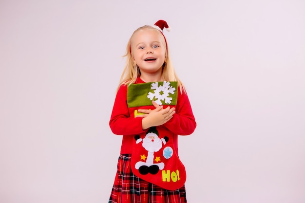 baby girl holding Christmas sock for gifts on white wall