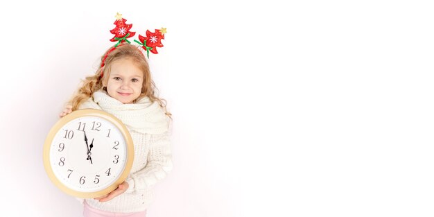 Baby girl holding a clock over white isolated background with the sweater