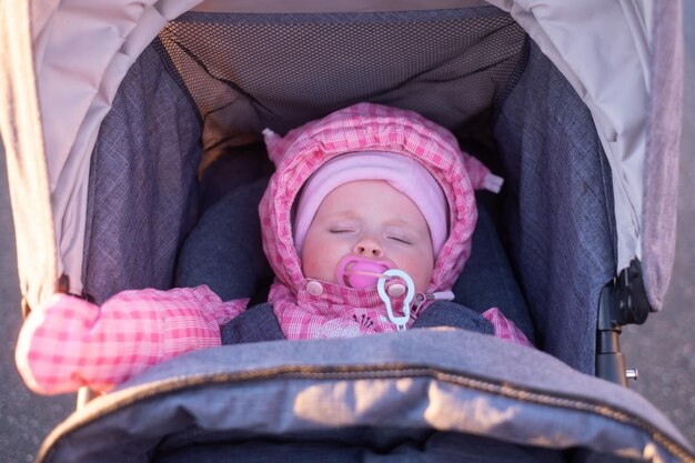 ベビーカーに座って散歩中にピンクの服を着た女の赤ちゃん