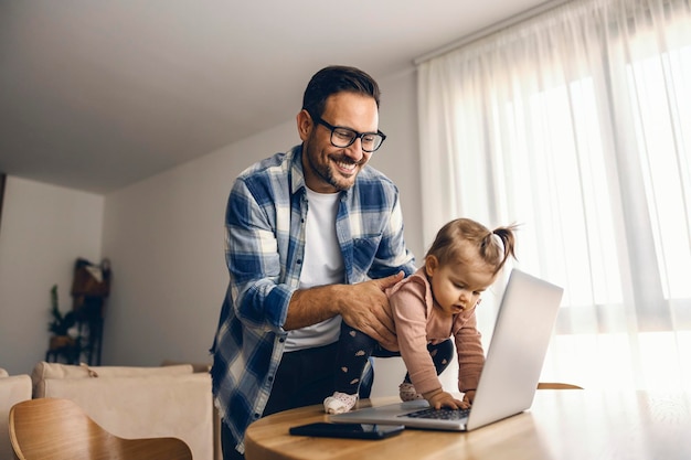 A baby girl is helping her freelancer dad to finish his job on a laptop