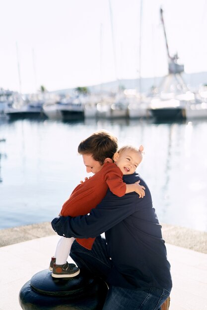 Девочка обнимает своего папу, проводя семейный день у моря.