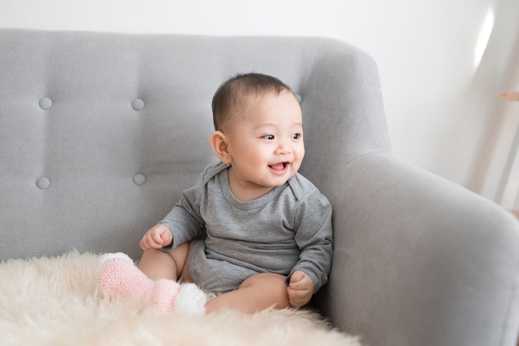 Photo 여자 아기는 웃 고 죄수 복에 소파에 앉아