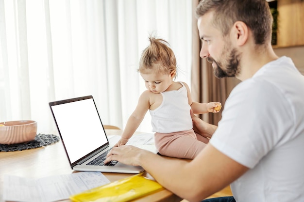 A baby girl is typing on a laptop and helping his father to finish a project