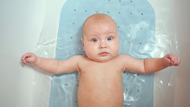 Baby girl lies in bath water and looks directly at parents