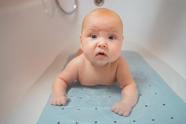 Baby girl lies in bathtub with water