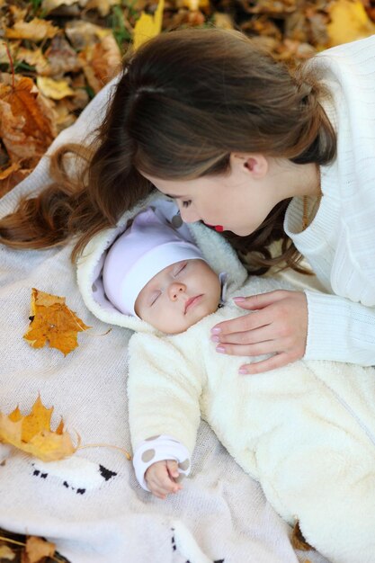 Baby girl an mom lying on carpet and autumn leaves