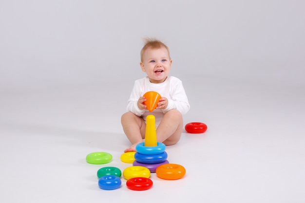 Baby girl playing  colorful rainbow toy pyramid sitting on floor