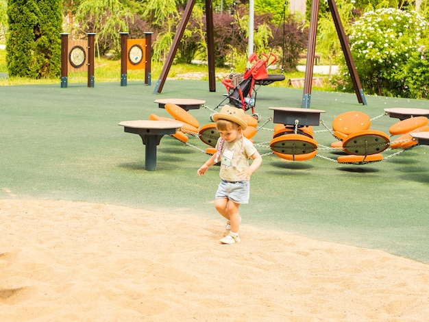 Photo baby girl playing in the sand on the playground on a summer day