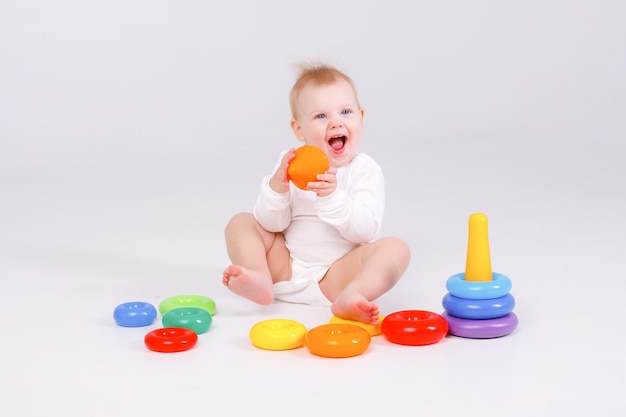 Baby girl playing with colorful rainbow toy pyramid sitting on floor