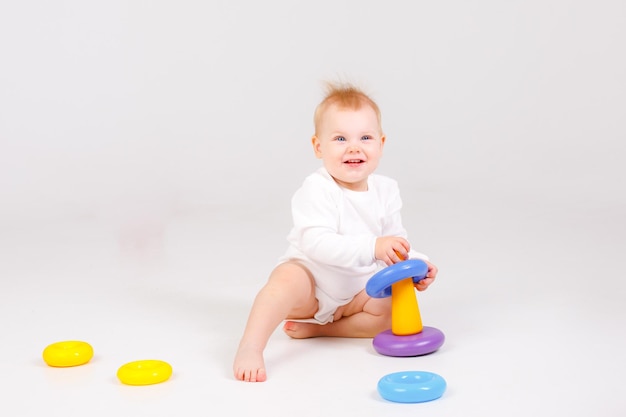 Baby girl playing with colorful rainbow toy pyramid sitting on floor