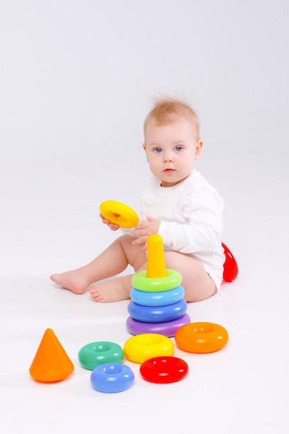 Baby girl playing with colorful rainbow toy pyramid sitting on floor