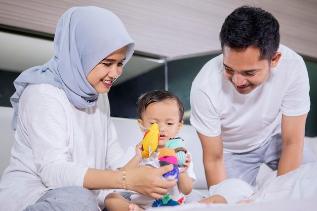 Baby girl playing with her parents on the bed