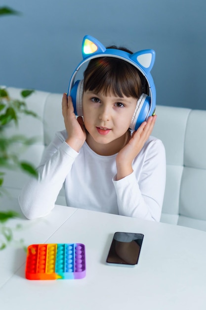 레인보우 팝을 가지고 노는 아기 소녀는 안절부절 못하고 헤드폰으로 음악을 듣는다