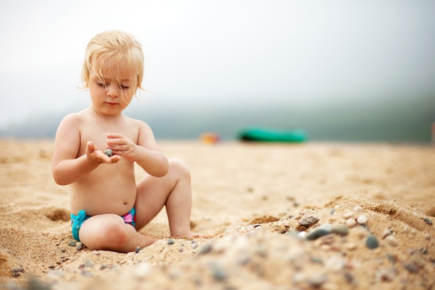 Baby girl playing with stones on a beach