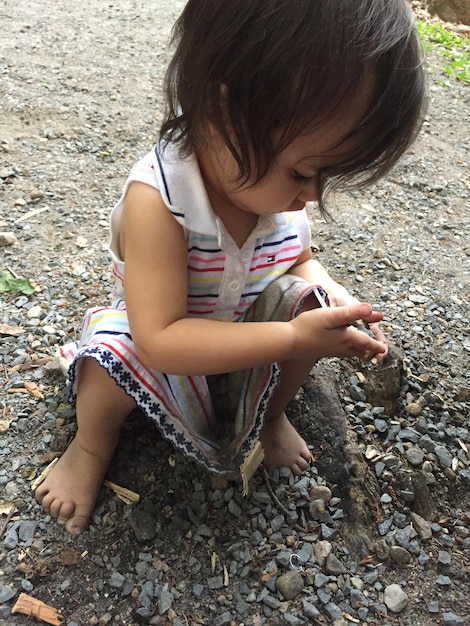 Девочка играет с камнями, сидя на суше.