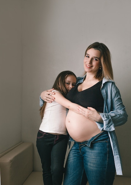 Baby girl and pregnant mother loving little sister next to mother's belly. happy family