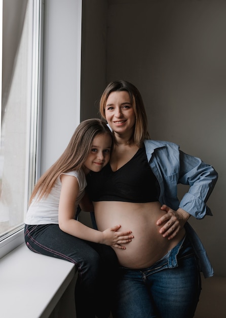 Neonata e madre incinta amorevole sorellina accanto alla pancia della madre. famiglia felice