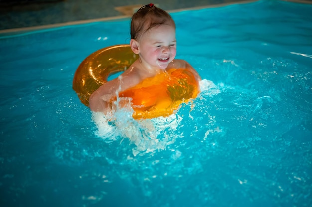 Baby girl in the private home swimming pool in a swimming circle enjoys splashing