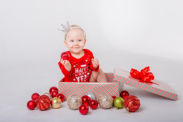 白い背景の上のギフト ボックスにサンタの衣装で女の赤ちゃんクリスマス ギフト