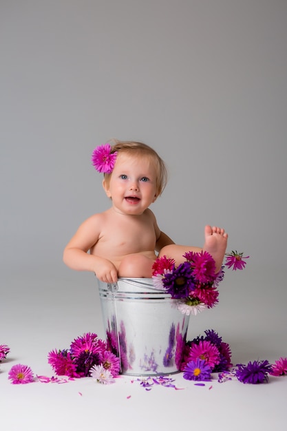 baby girl sitting in a bucket of flowers