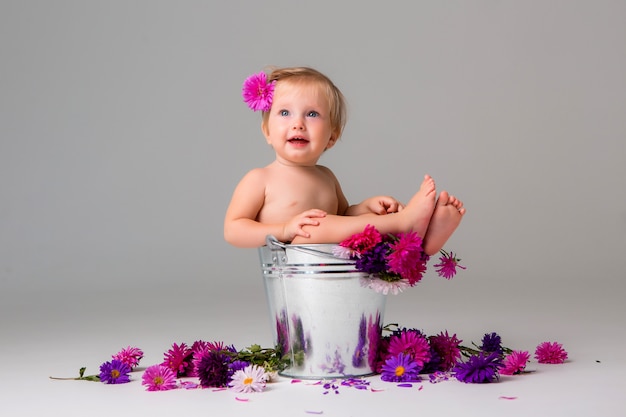 baby girl sitting in a bucket of flowers