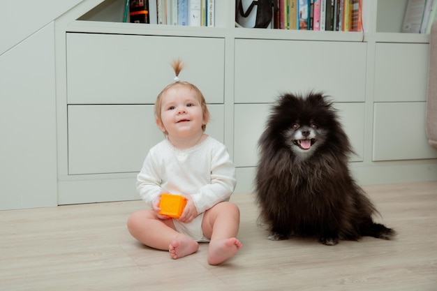 犬の赤ちゃんのコンセプトとペットの隣の床に座っている女の赤ちゃん