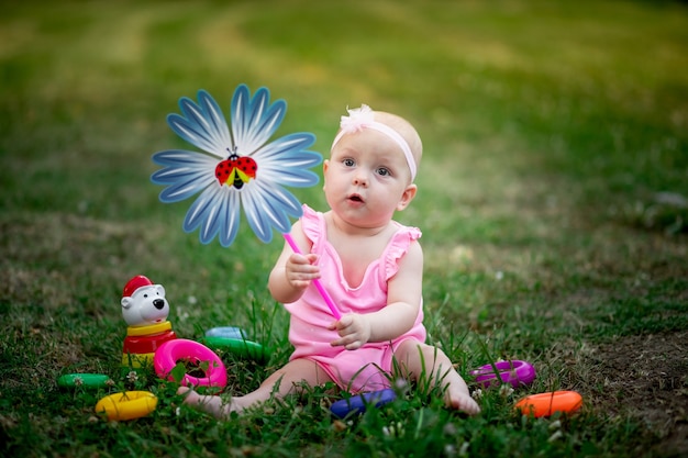 baby girl sitting on the grass in the summer and playing with a turntable