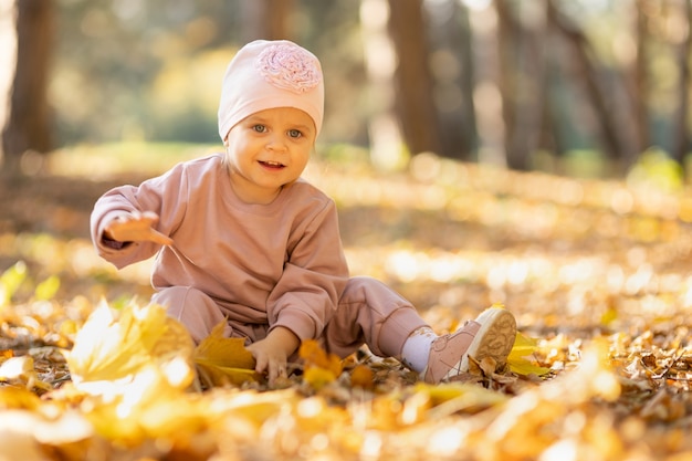 紅葉で地面に座っている女の赤ちゃん、2歳