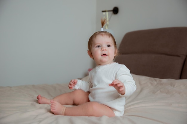 自宅の寝室のベッドに座っている女の赤ちゃん