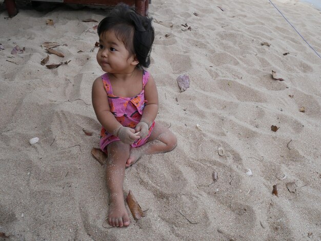 Baby girl sitting on sand at beach