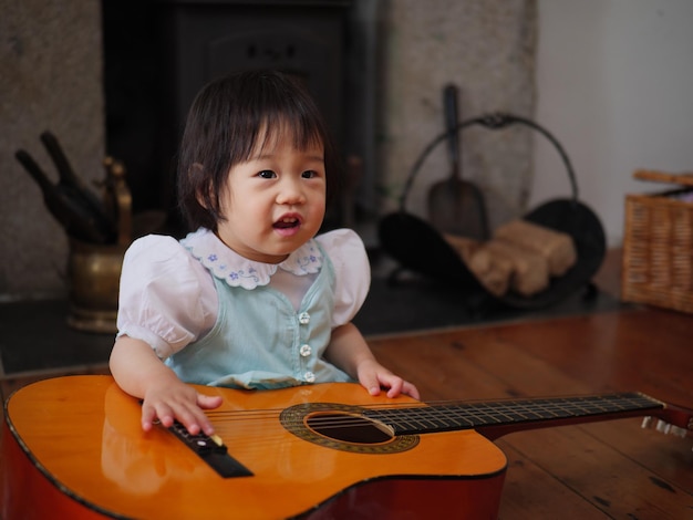 Photo baby girl sitting with guitar at home