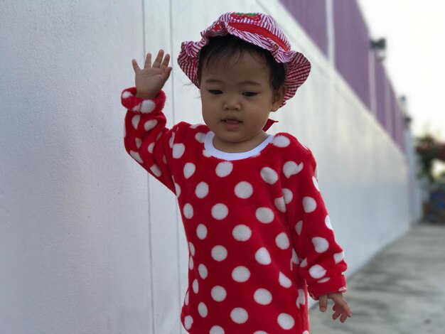 Baby girl standing by wall