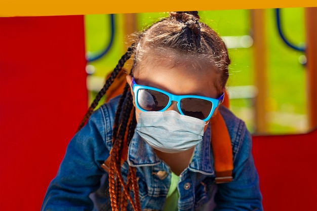 Photo baby girl in sunglasses in a medical mask on the face