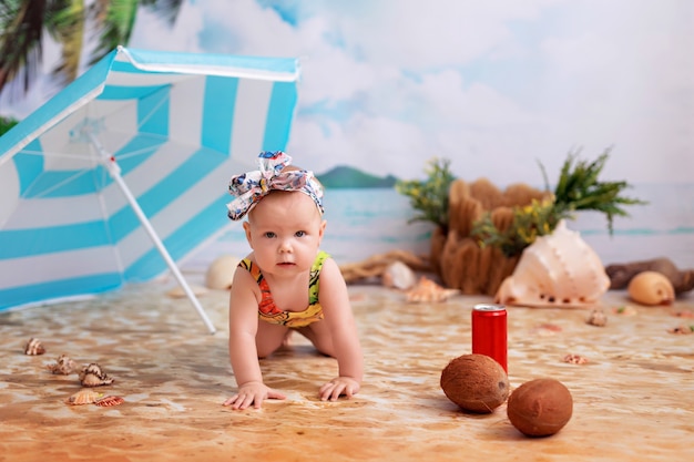 Baby girl in a swimsuit on a sandy beach