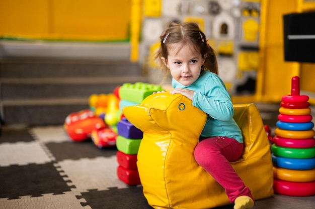 Baby girl swings on yellow paralon duck at kindergarten