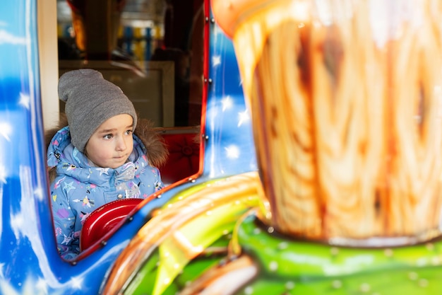 Baby girl in train carousel in amusement park