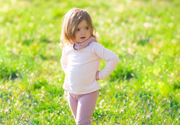 Baby girl walking in green grass Child having fun on family picnic in summer garden