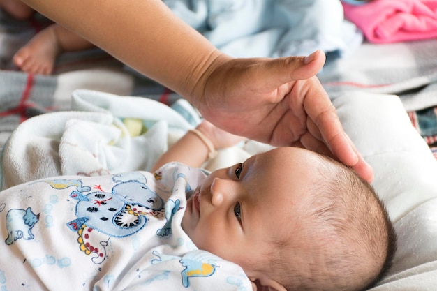 Photo the baby girl was lying on a white cloth with her mothers hand touching the forehead